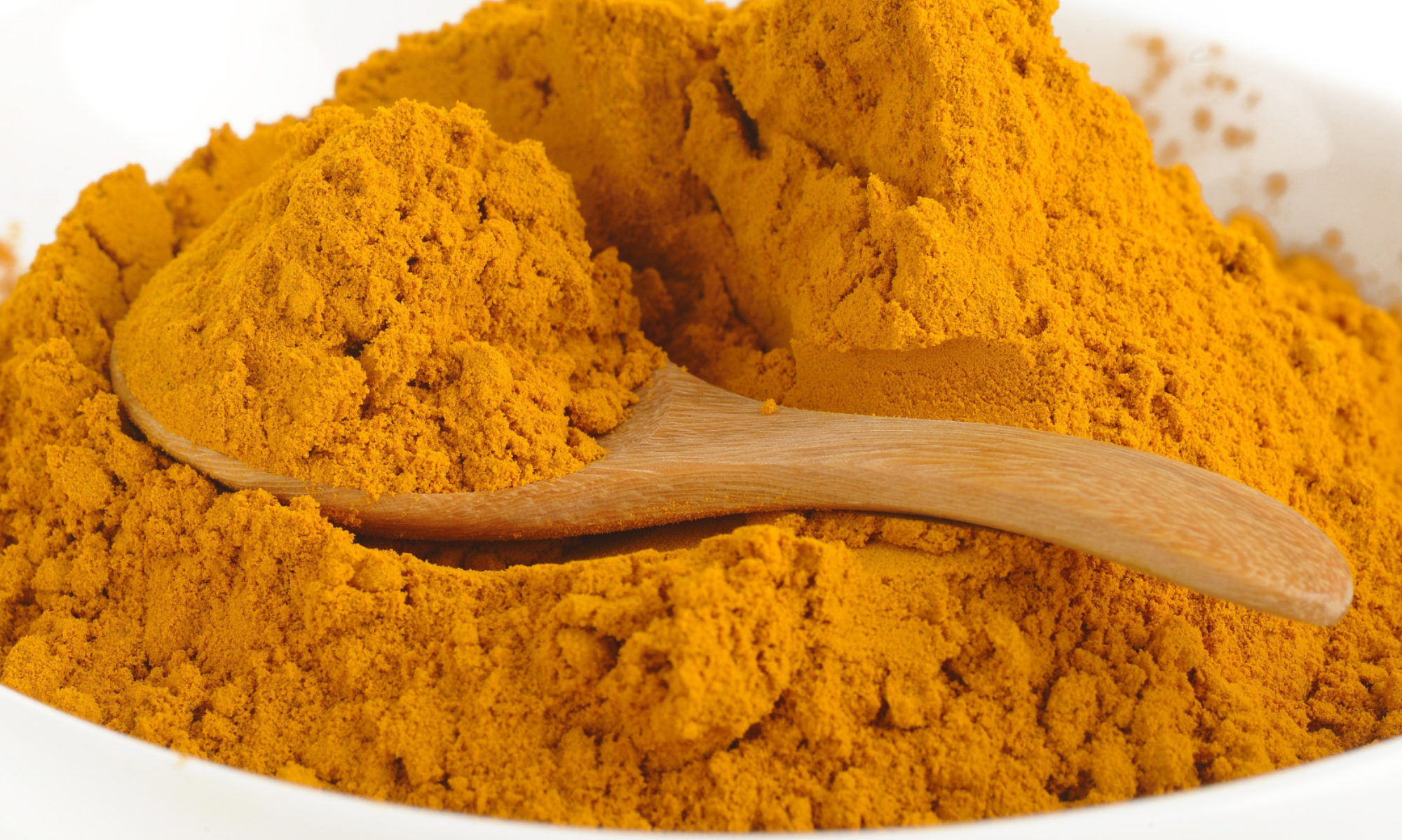 Golden turmeric piled on a wooden spoon